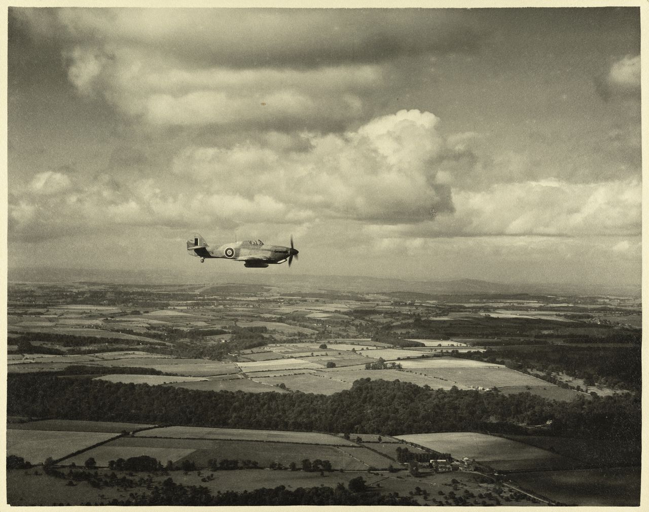 Still from a film produced by the RAF Film Production Unit during the Second World War, showing a 'hurribomber' - a fighter bomber variant of the Hawker Hurricane - in flight