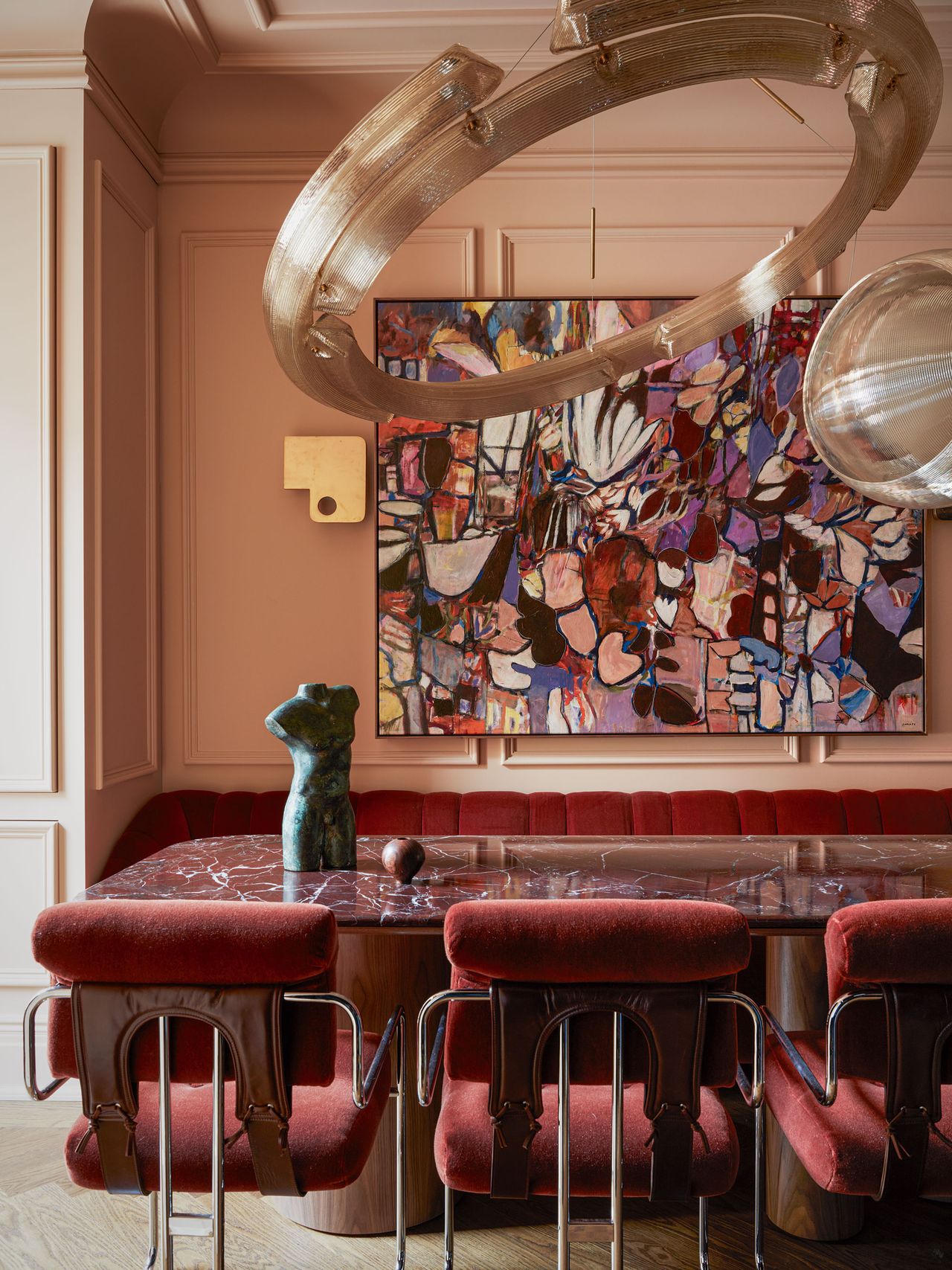 a pink dining room with red chairs and red marble table