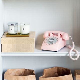 pink telephone next to decorative box with two candles on top