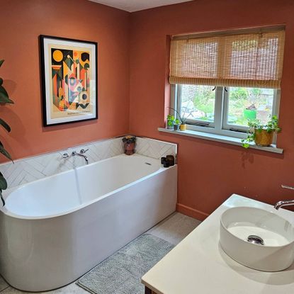 red bathroom with large bath and bamboo blinds