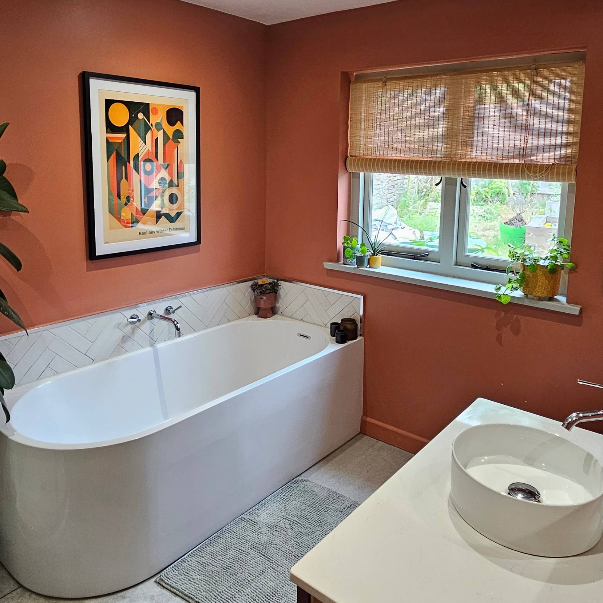 red bathroom with large bath and bamboo blinds