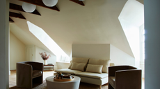 simple, minimalist loft conversion living room with large windows, wooden beams and linen lights