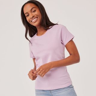 A woman wears a lilac crew neck tee.