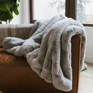 Cozy Earth Cuddle Blanket on a brown armchair. 