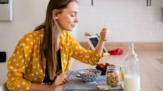 Young woman enjoying breakfast in kitchen at home