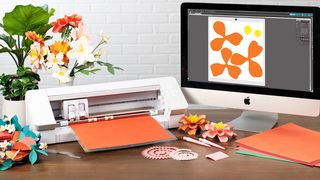 The best Silhouette machines, as represented by a photo of a cutting machine next to a Mac
