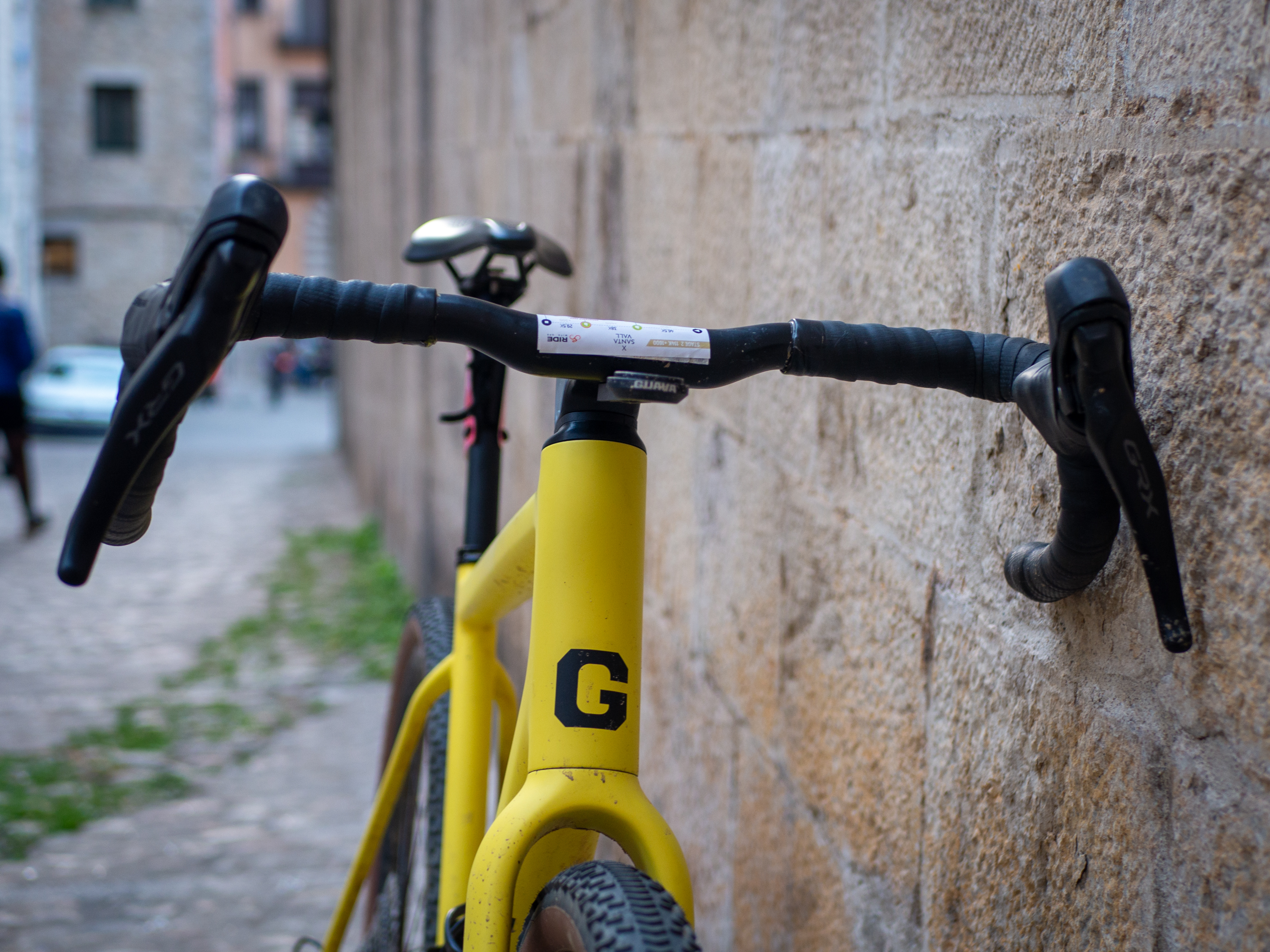 A yellow Guava Spot gravel bike leans against a wall