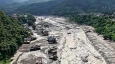 Houses lie partially submerged in muddy water along a riverside after flash floods at Trishuli Bazar in Nepal's Nuwakot district.