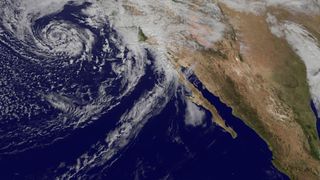 A satellite image of the eastern Pacific Ocean off Baja California with clouds.