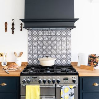 Black and white kitchen with tiled splashback and extractor fan over a range cooker