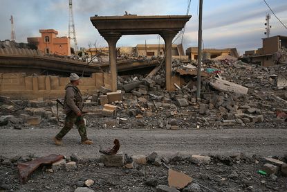 A peshmerga soldier walks by rubble in Sinjar, Iraq.