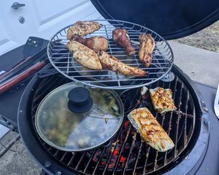 food cooking on a kamado grill with meat on a warming rack