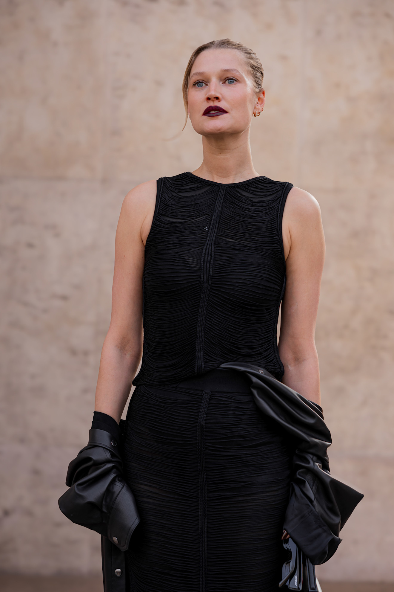 a woman in a black dress with blonde hair and a dark maroon lipstick