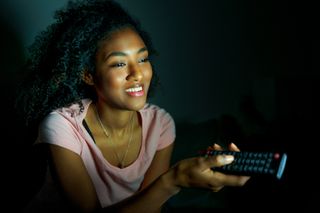 Young black woman watching tv late at night