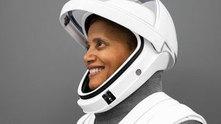 a woman smiles while posing for a portrait in a white spacesuit