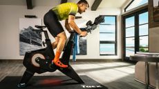 A man riding one of the best smart bikes indoors, the Garmin Tacx Neo Bike Plus