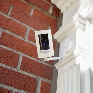 White security camera mounted to the outside of a house