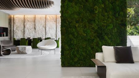 Dividing moss wall in modern, white open plan living space with cool staggered seating