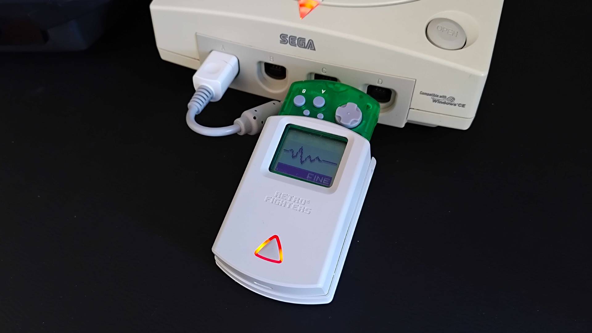 Retro Fighters StrikerDC VMU cradle connected to console with Resident Evil: Code Veronica life meter displayed with "fine" text underneath.