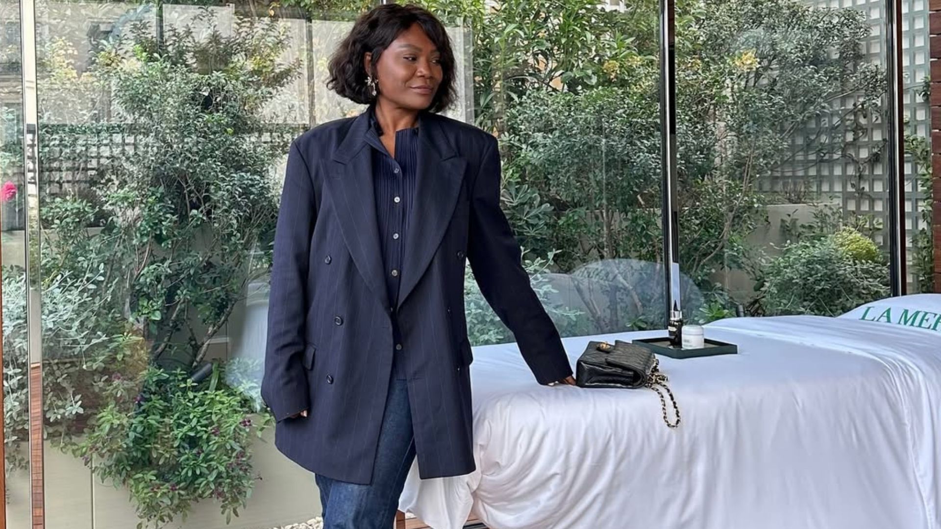 Franny Mozemba is photographed wearing a navy pinstripe blazer and navy button-up top with dark jeans.