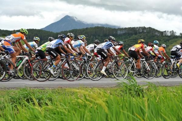 The riders of Tour de Singkarak 2012 through the rice fields with a background Mount Marapi at stage 3 .