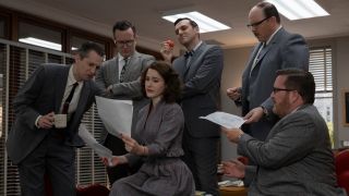 Rachel Brosnahan as Midge Maisel reviewing a bunch of papers with writers around her in Season 5 of The Marvelous Mrs. Maisel.