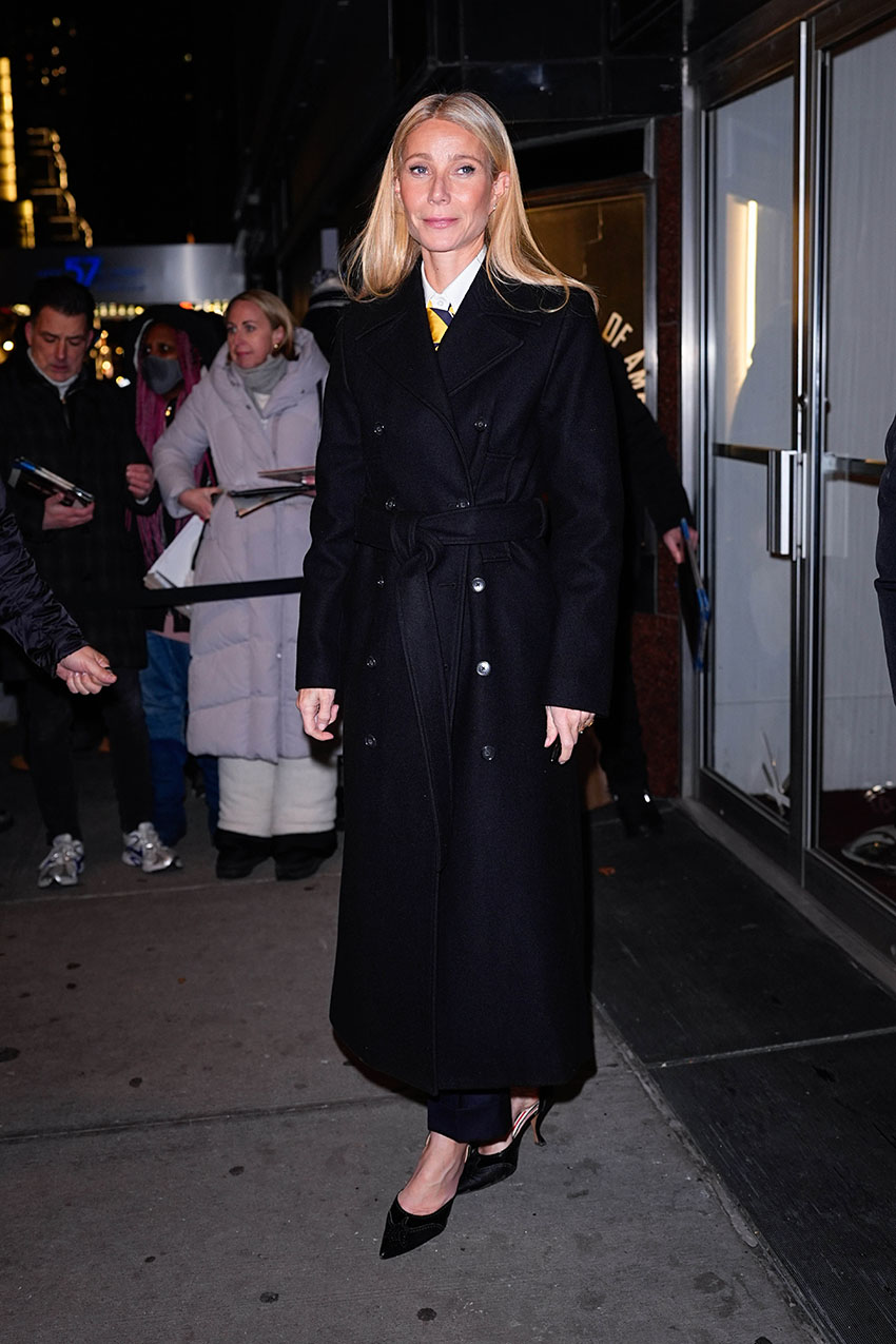 Gwyneth Paltrow wearing a black belted coat and black heels