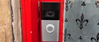 The Ring Video Doorbell 4 installed on a red door frame