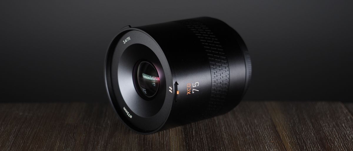 Hasselblad XCD 75P lens, on a wooden surface, against a dark background