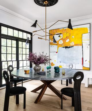 dining room with round table and white walls and bright contemporary artwork