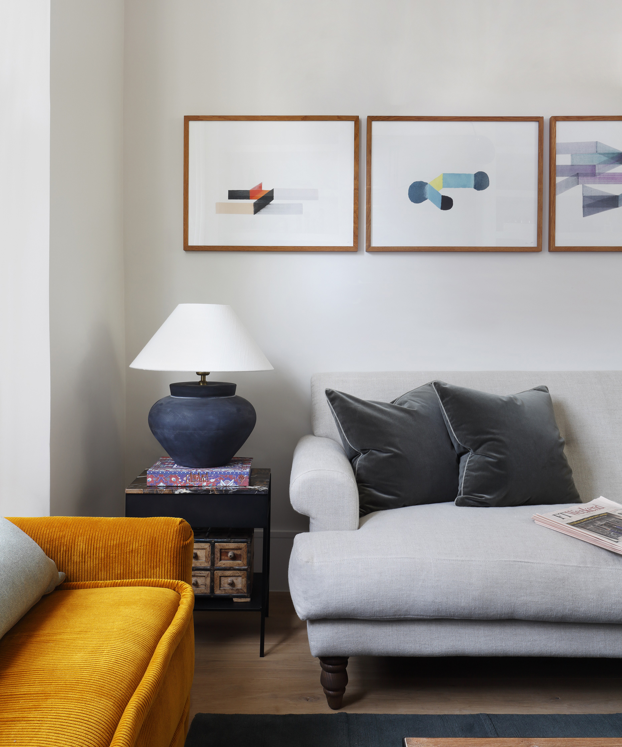 pale living room with grey sofa against the wall and yellow sofa at an angle to it