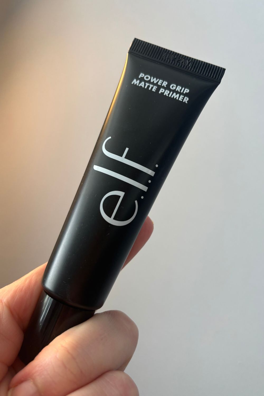 a hand holding a tube of elf primer