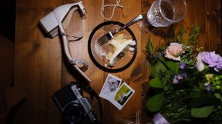A film camera with half-eaten wedding cake, a tie, and a bride's shoe