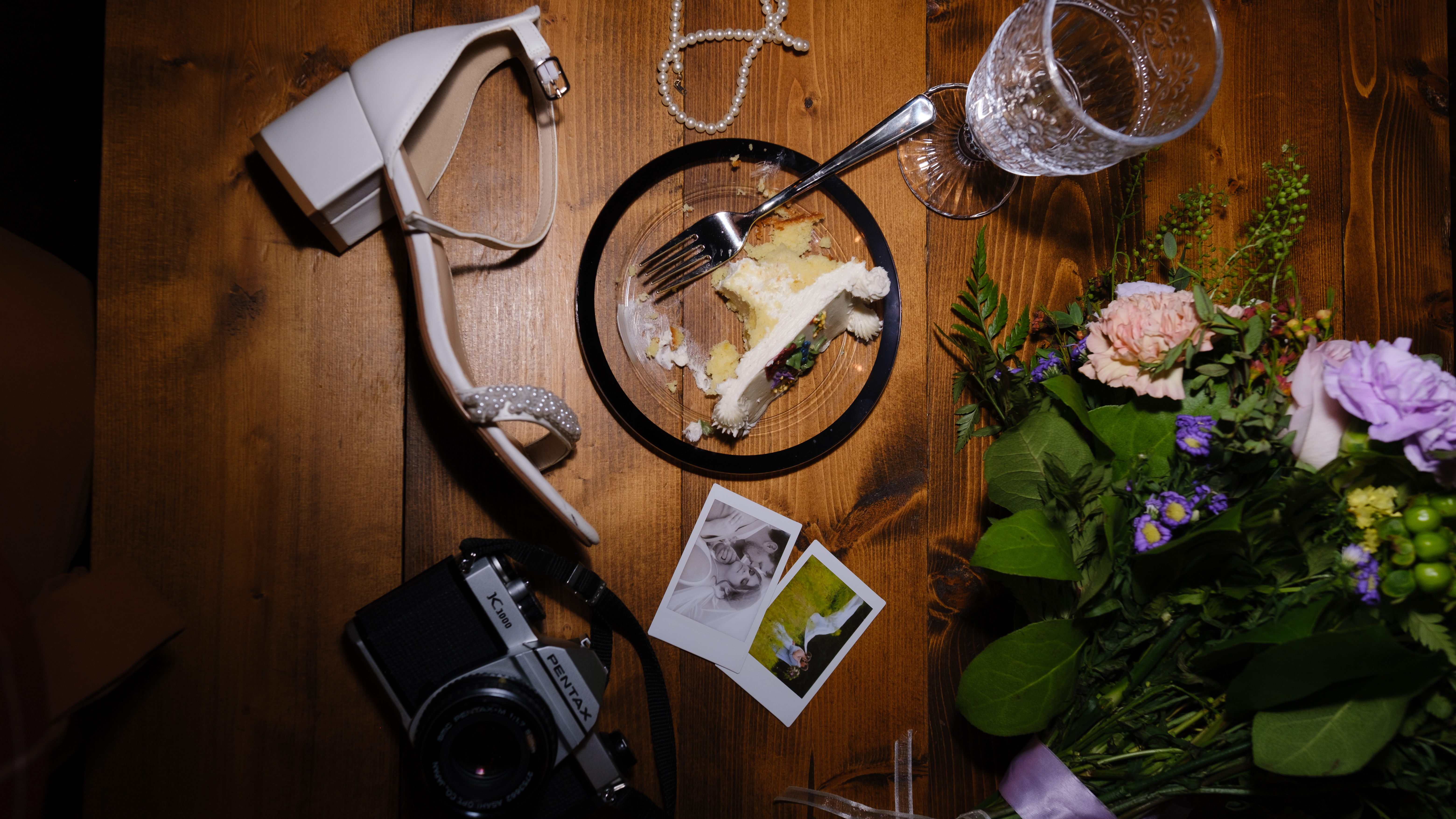 A film camera with half-eaten wedding cake, a tie, and a bride&#039;s shoe