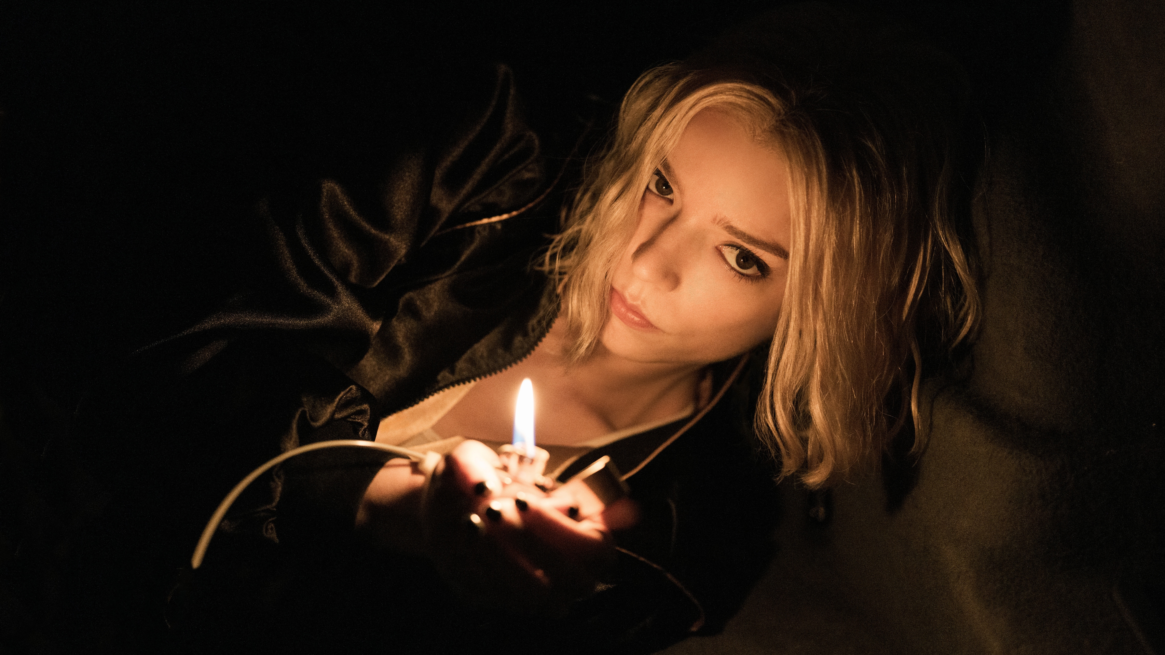 Anya Taylor-Joy as Lucky holding a lighter in a dark space.