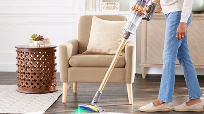 QVC Dyson Deals - Dyson Vacuum in a home with a green laser vacuuming around a chair on a hard surface