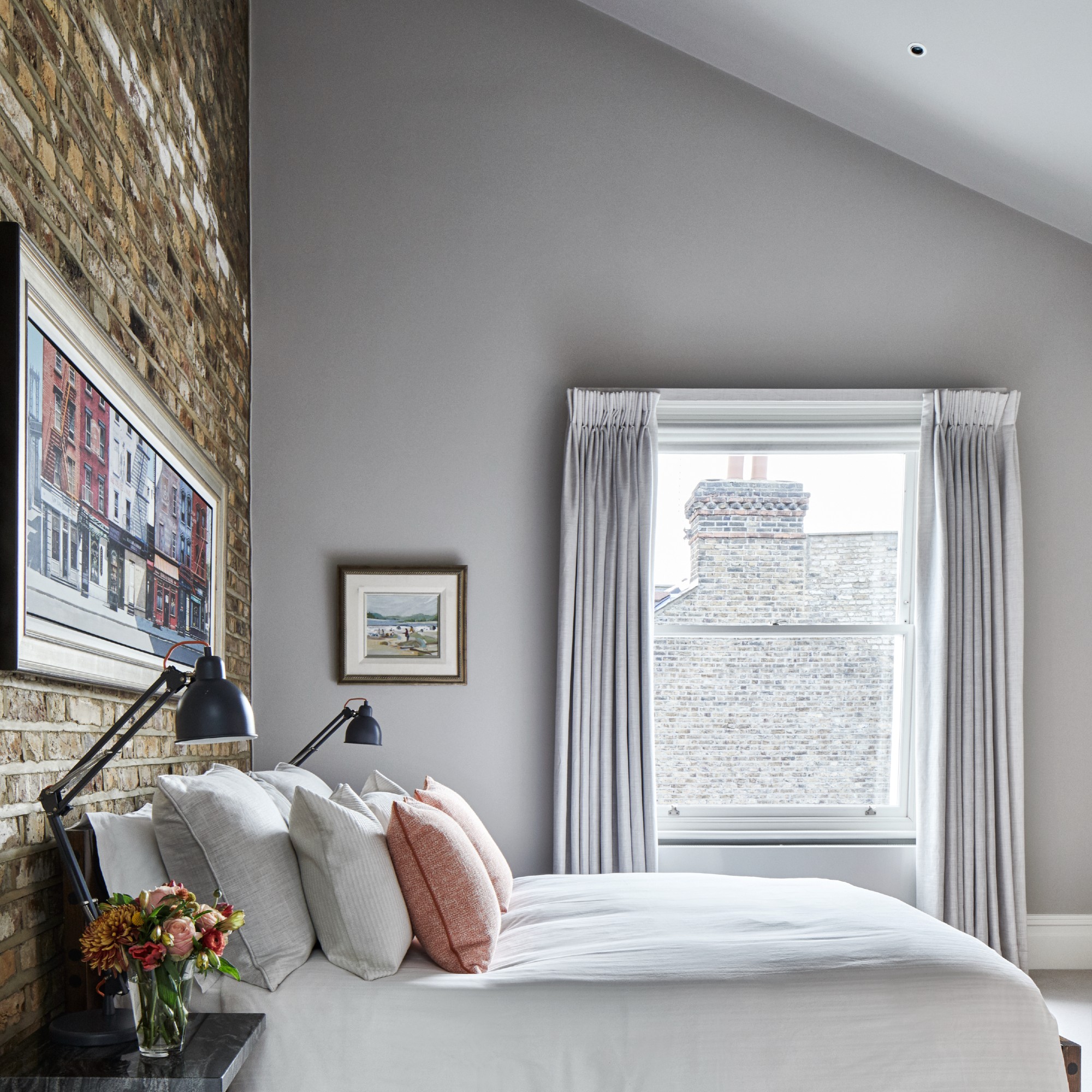 A bedroom with a light grey-painted feature wall and tonal curtains