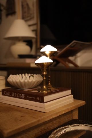 Two diamond shaped puck lights in brass candle holders on a stack of books