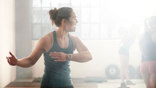 Woman warming up to exercise in indoor gym, smiling