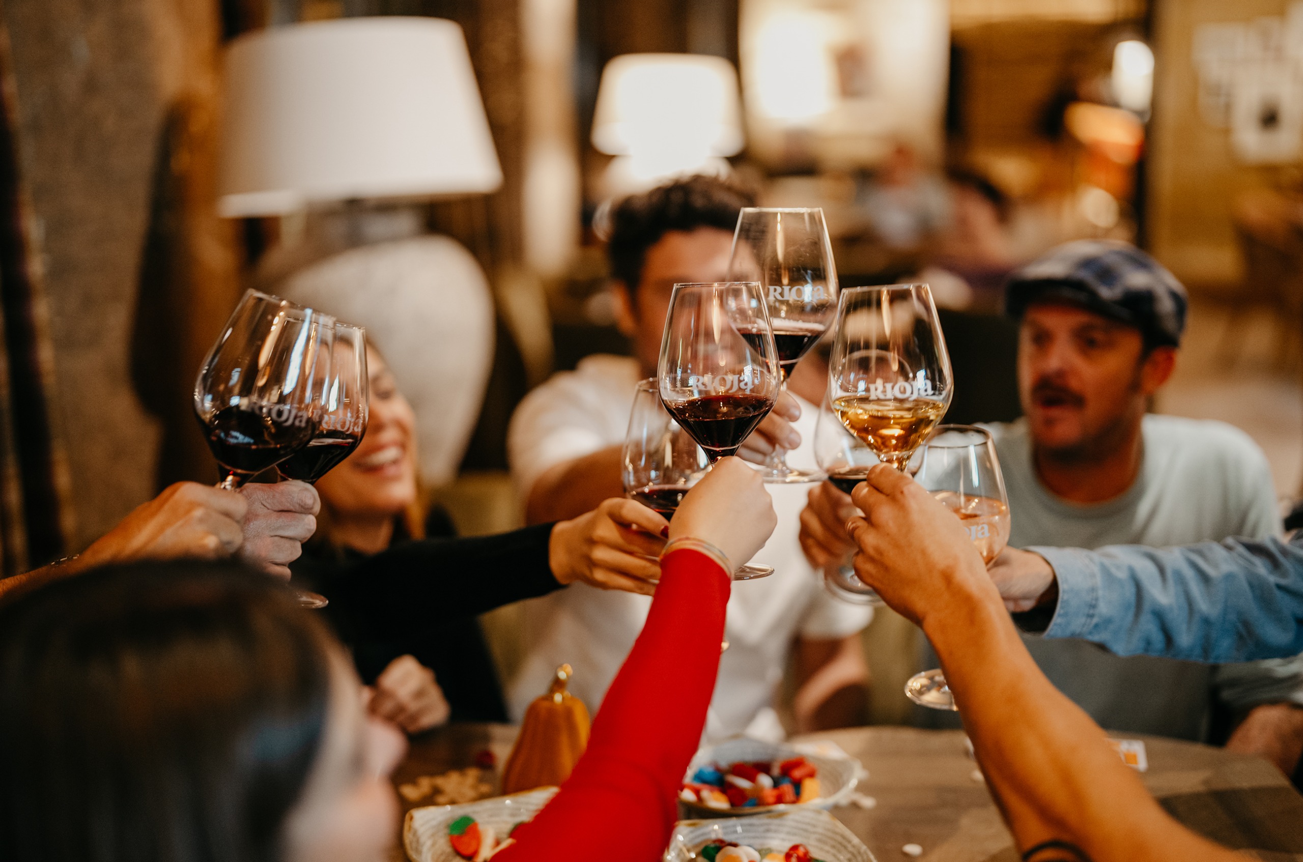 A group of people at a table raising glasses of red and white wine together