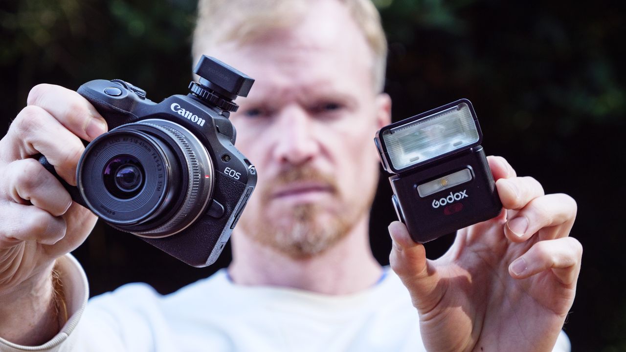 Godox iT32 camera flash alongside a Canon camera, held by photographer and TechRadar's Cameras Editor Tim Coleman,