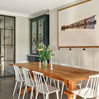 open plan kitchen with white built-in cupboards, wooden dining table with hero artwork