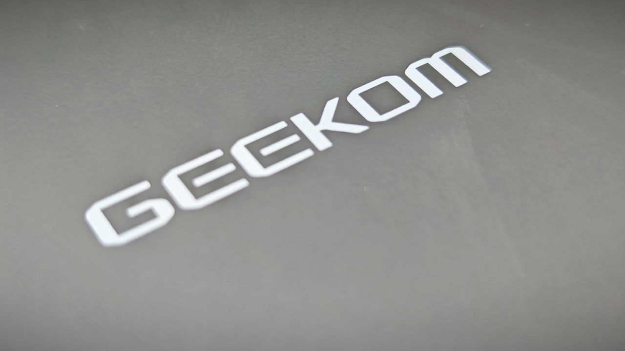 A black Geekom IT15 mini PC sitting in a grassy field