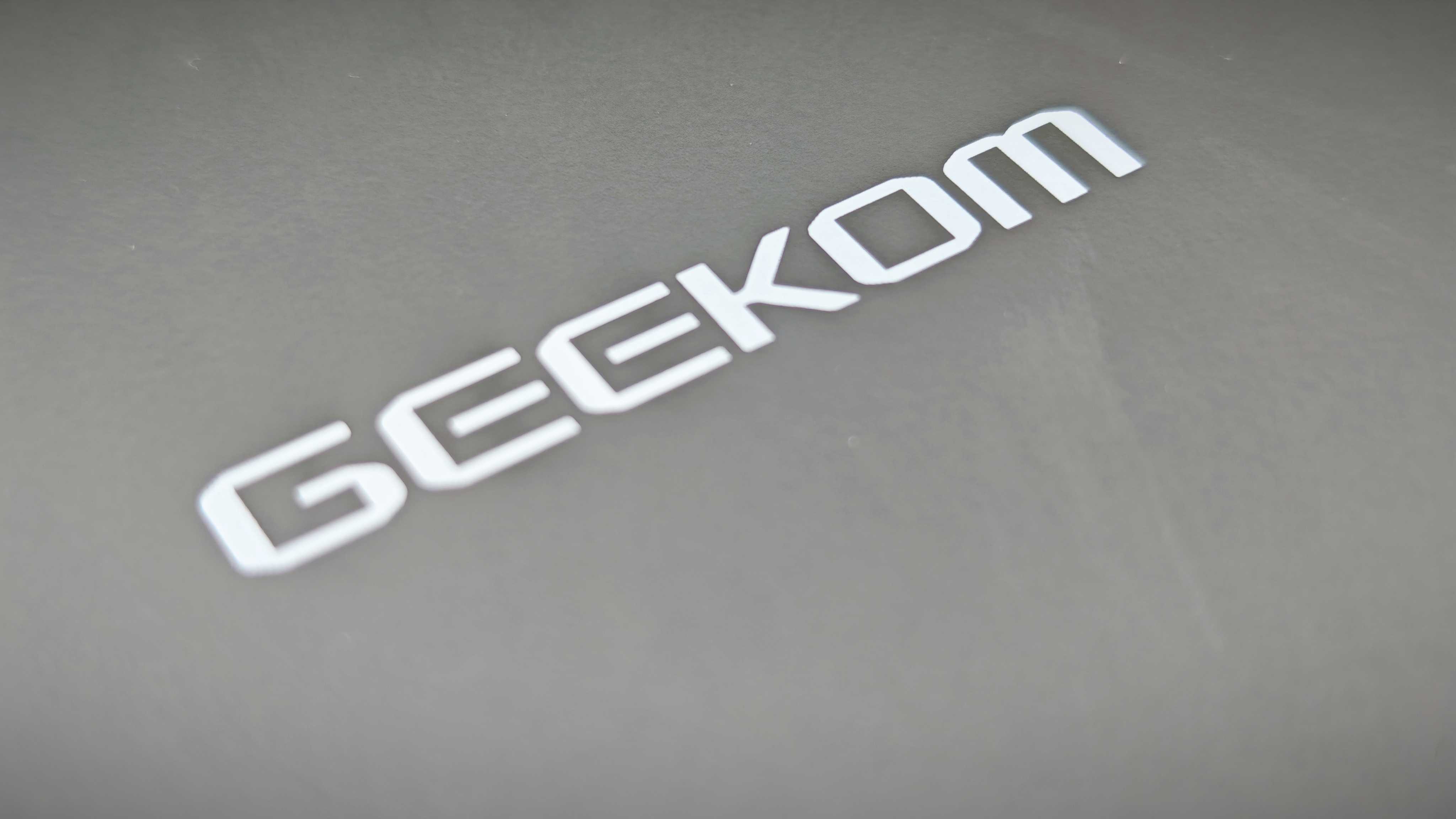 A black Geekom IT15 mini PC sitting in a grassy field