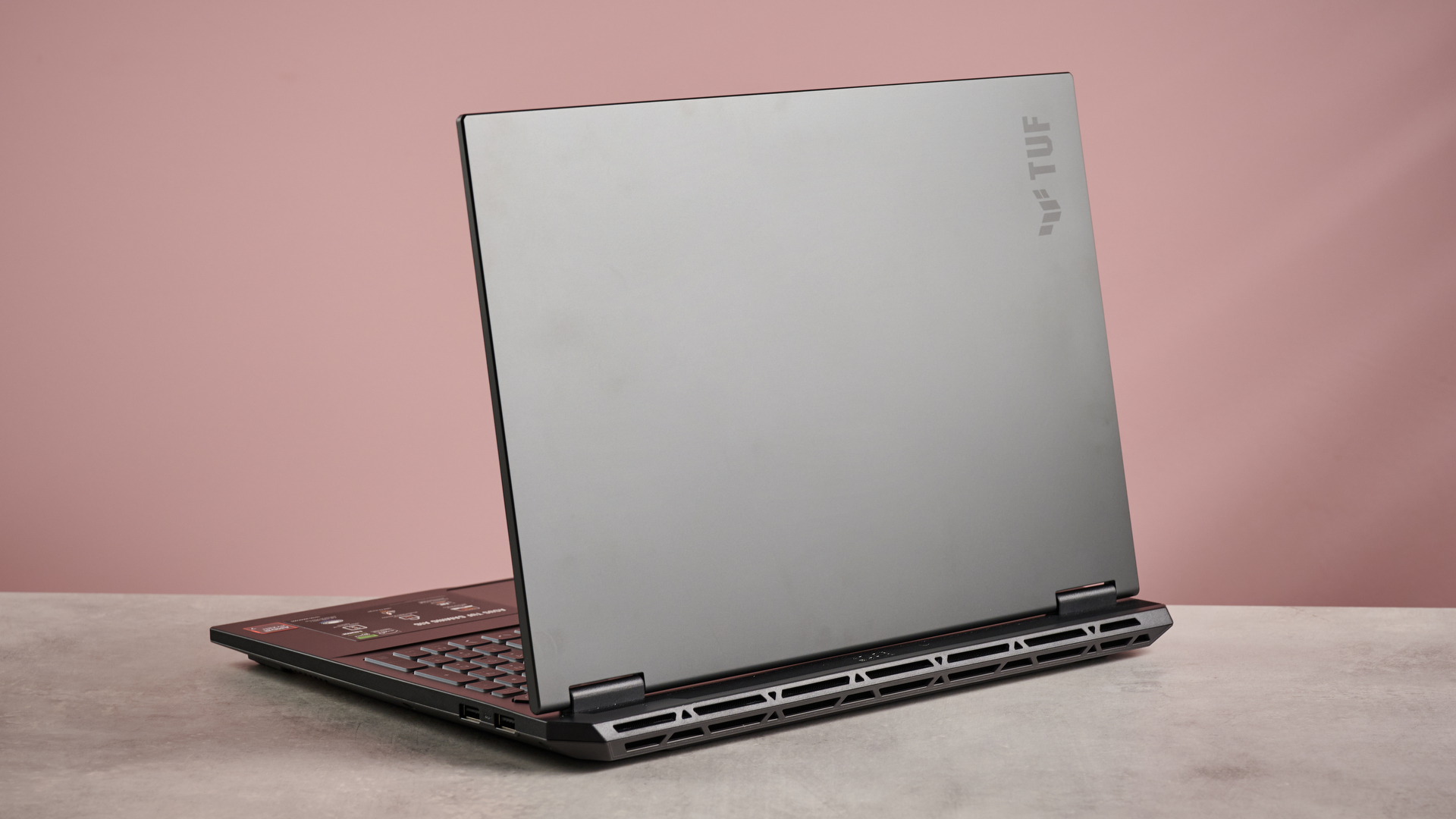 Back of ASUS TUF Gaming A16 (2025), open on desk with pink background