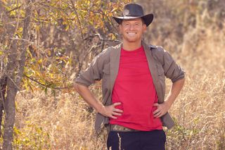 Joe Swash wearing a hat and red t-shirt posing in South Africa