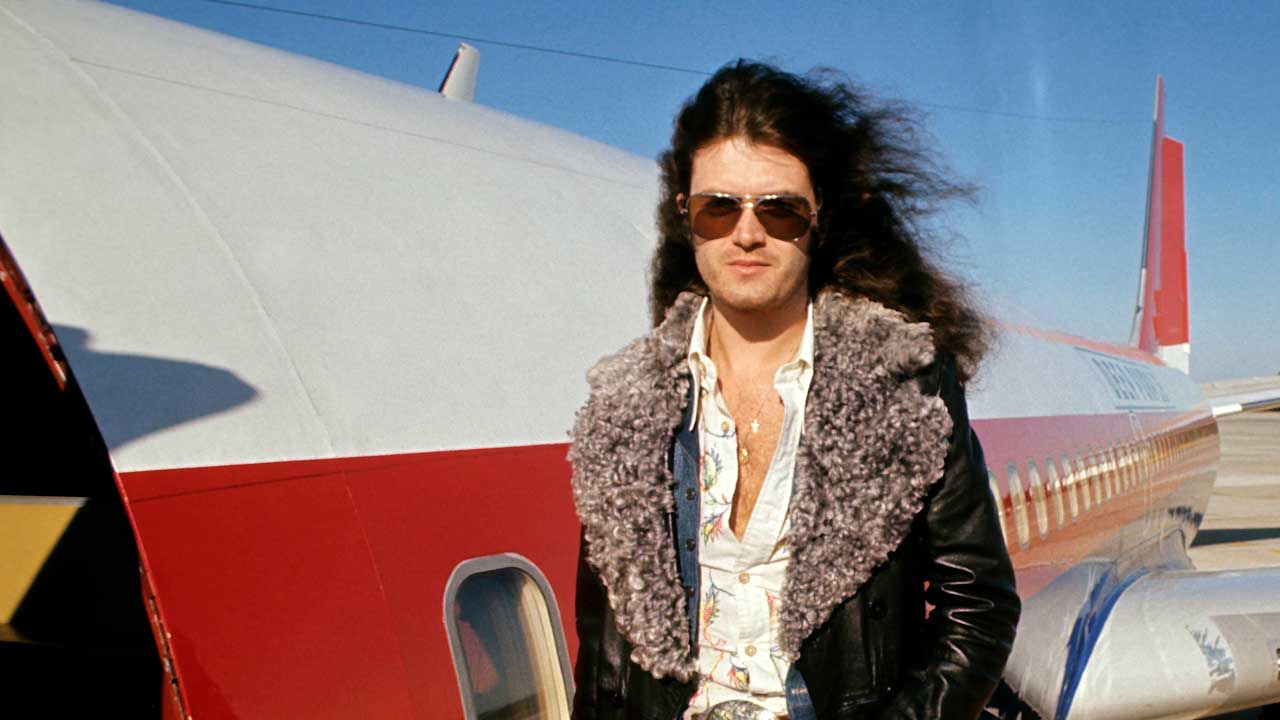 Glenn Hughes, posed, standing by plane  