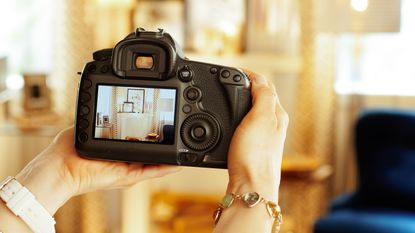 A woman holds a camera as she takes photos of the interior of a home for sale.