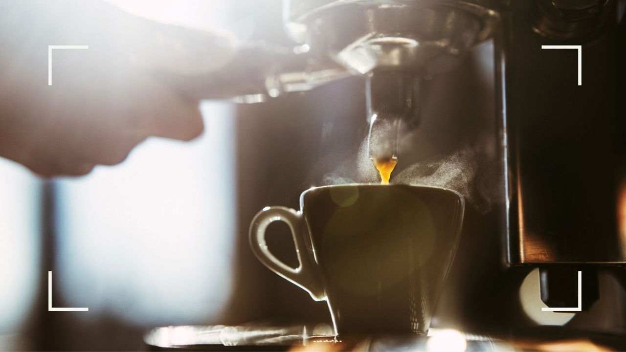 Barista coffee machine pouring espresso with sunlight streaming over the machine