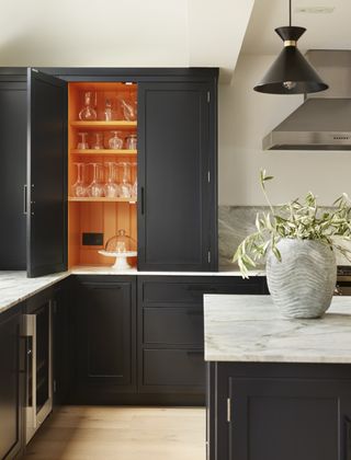 Kitchen with black cabinetry with orange interior and island